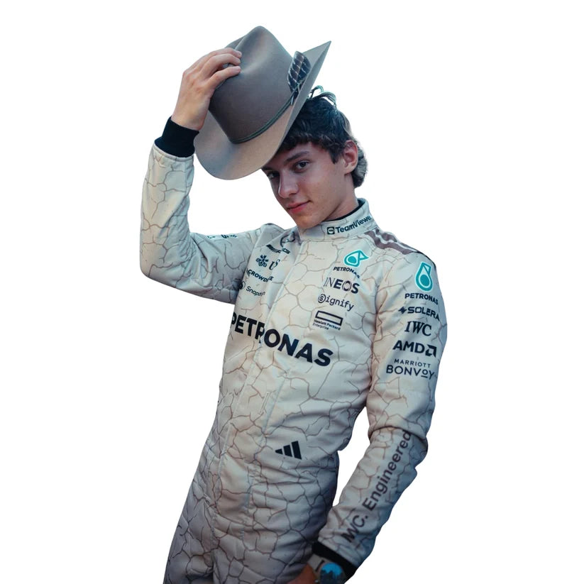 Andrea Kimi Antonelli in Mercedes 2025 USA Austin GP F1 Racing Suit holding a cowboy hat, with sponsor logos including Mercedes, Petronas, Michelin, and IWC on the suit, against a plain white background.