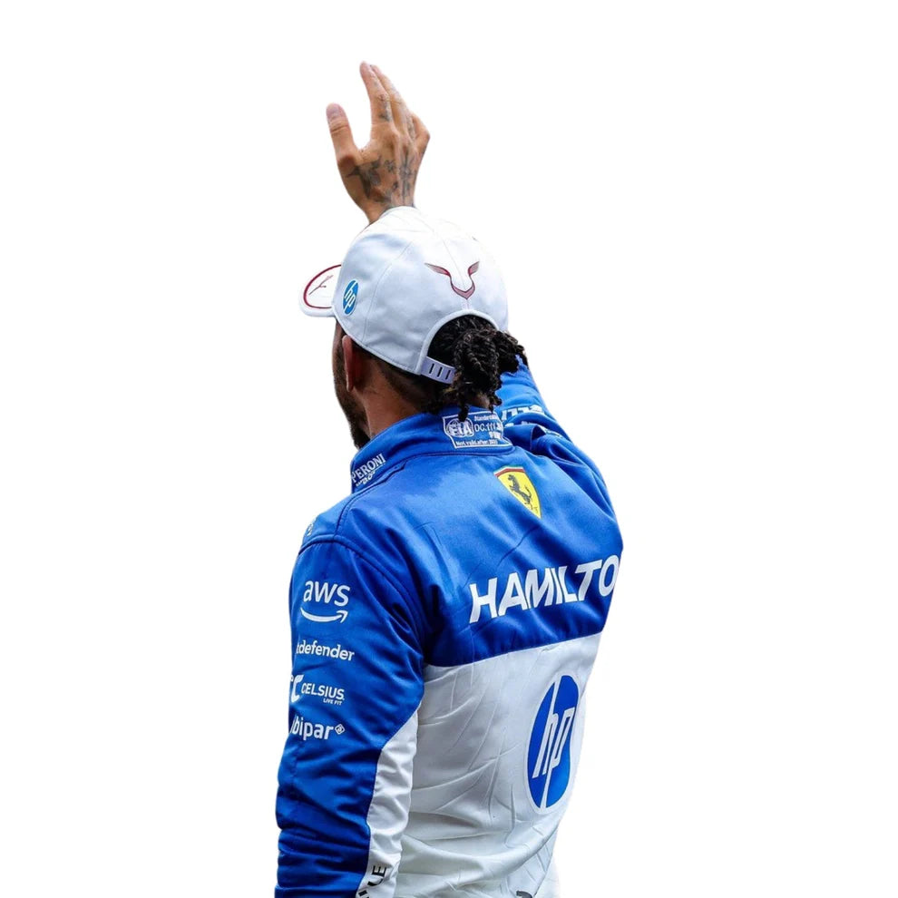 Lewis Hamilton wearing a blue and white Ferrari racing jacket with various sponsor logos on a white background
