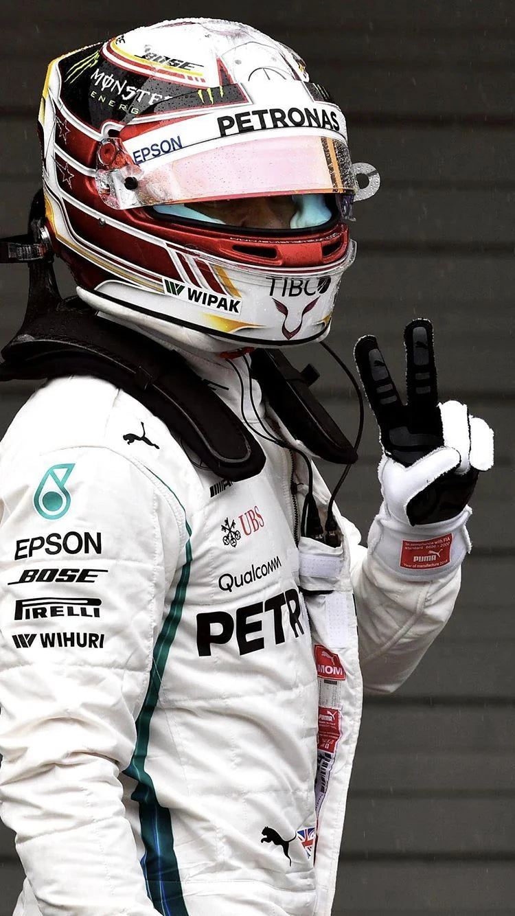 Person wearing a Formula 1 racing suit and helmet with visible branding