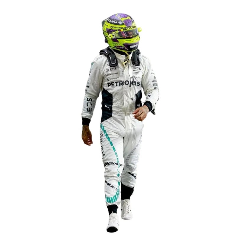 Lewis Hamilton wearing a white Mercedes racing suit with black and teal accents, along with a neon yellow and purple racing helmet, walking against a plain white background.